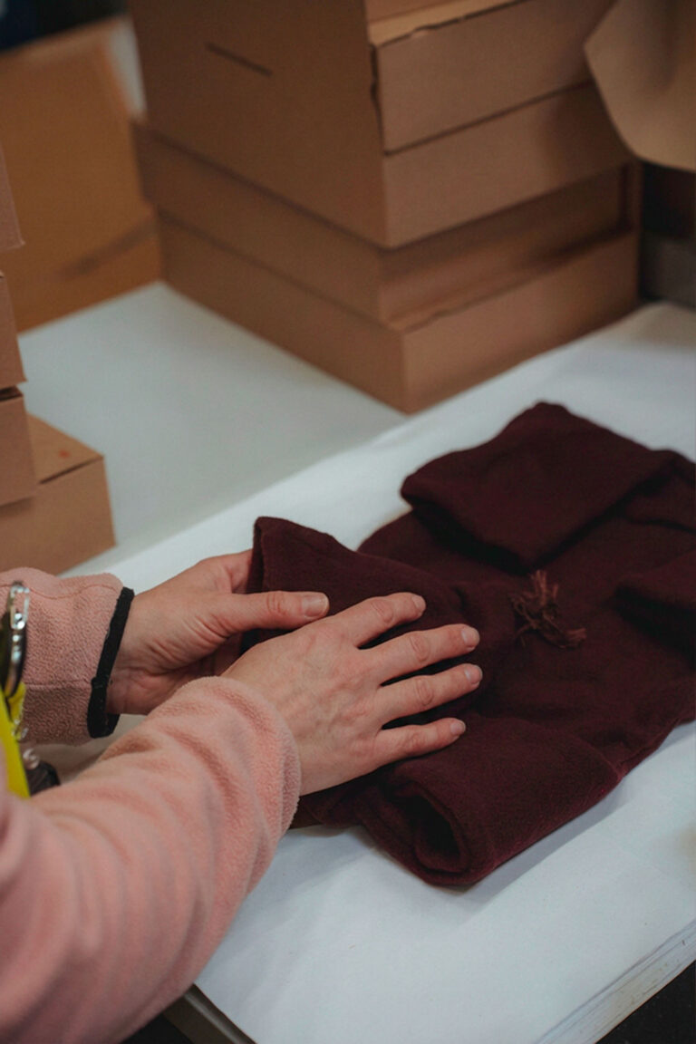 Hände falten Kleidung auf einem Packtisch