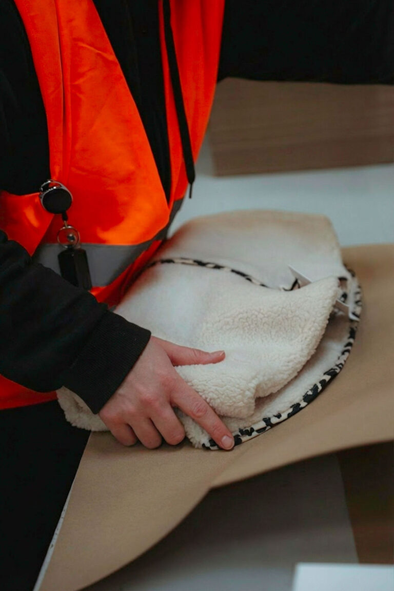 Hände falten Kleidung in Packpapier