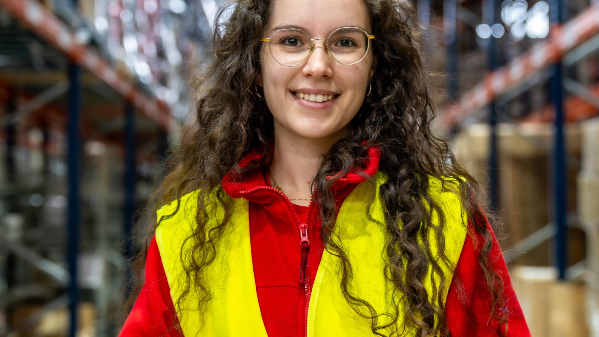 Vertical portrait of a woman in reflective waistcoat working holding scanner in a distribution warehouse